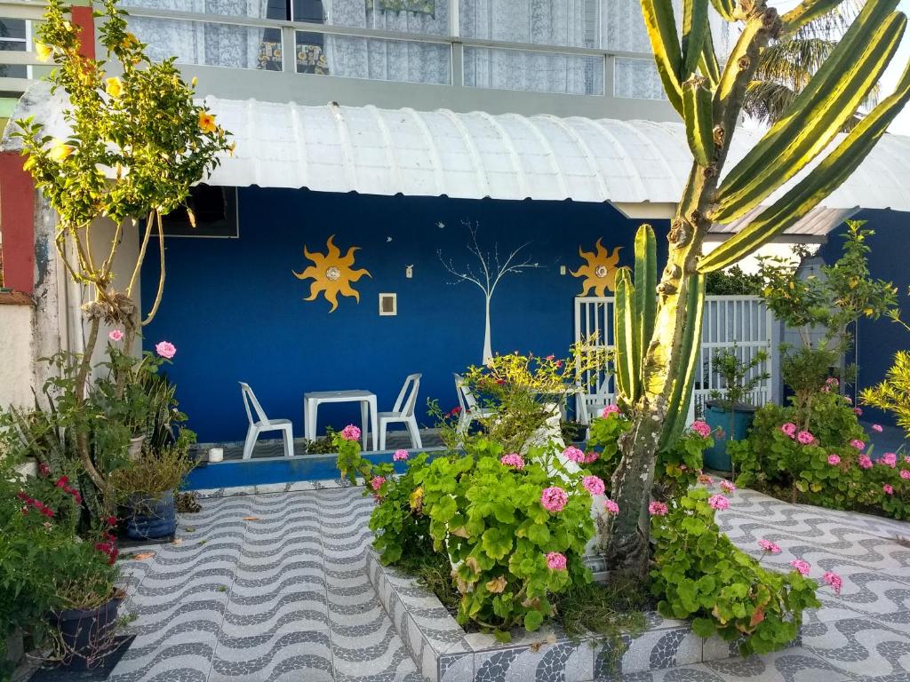 a blue building with plants and flowers in a courtyard at Apartamentos Águia Suíte casal 2 in Ilha Comprida