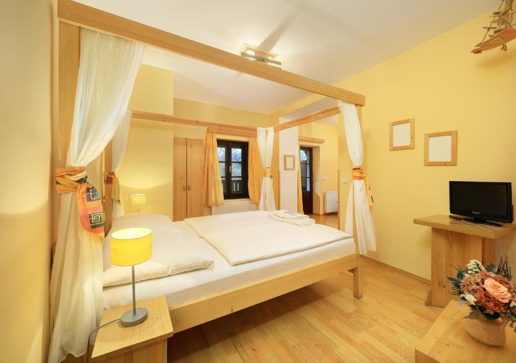 - une chambre avec un lit à baldaquin et une télévision dans l'établissement Hotel Garni Myší Díra, à Český Krumlov