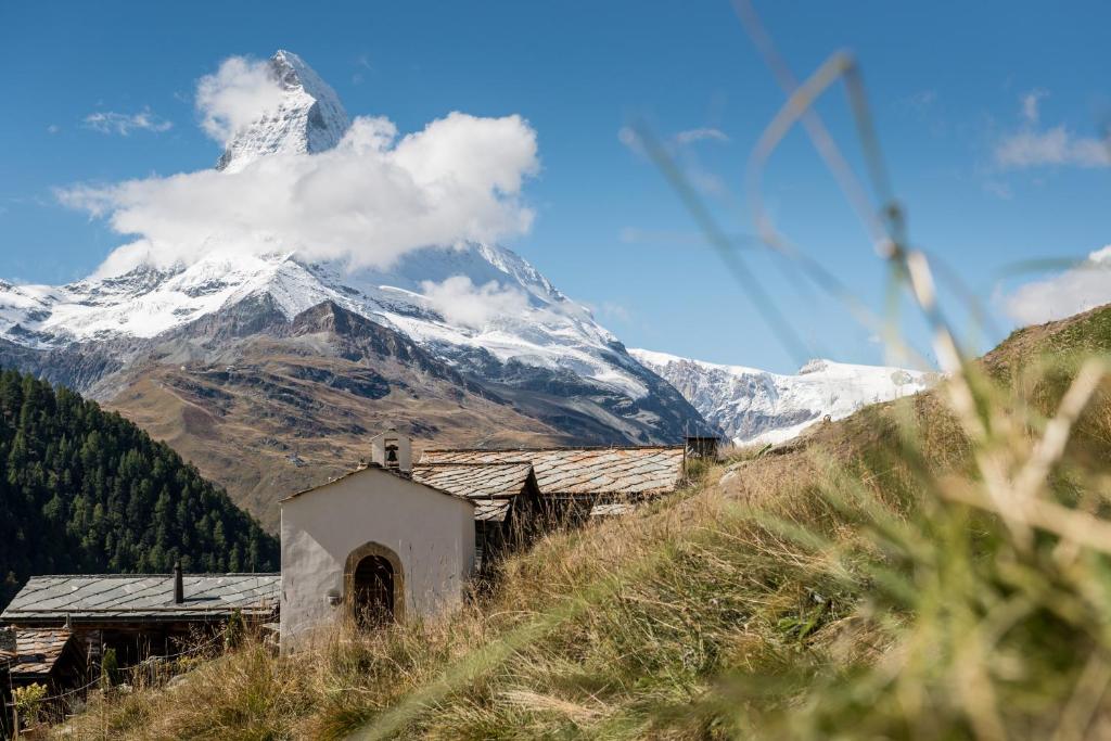 an old building on a hill with a mountain in the background at Apartments Butterfly Zermatt in Zermatt