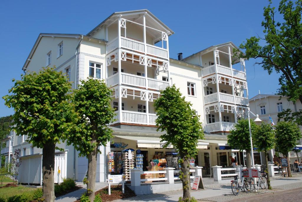 un gran edificio blanco con árboles delante de él en Villa Seerose - Appartement 02, en Ostseebad Sellin