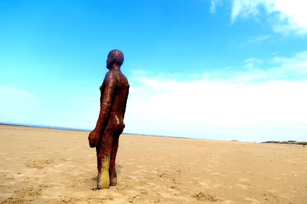 une statue d'une personne debout sur la plage dans l'établissement Beach house, à Crosby