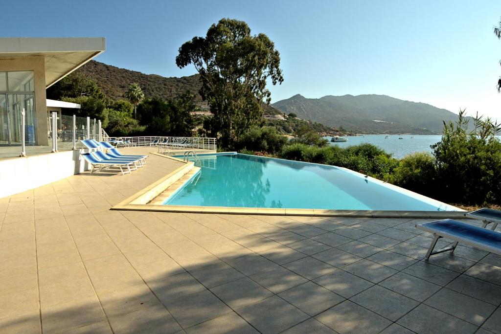 a swimming pool with chairs and a view of the water at Hotel la Parata in Ajaccio