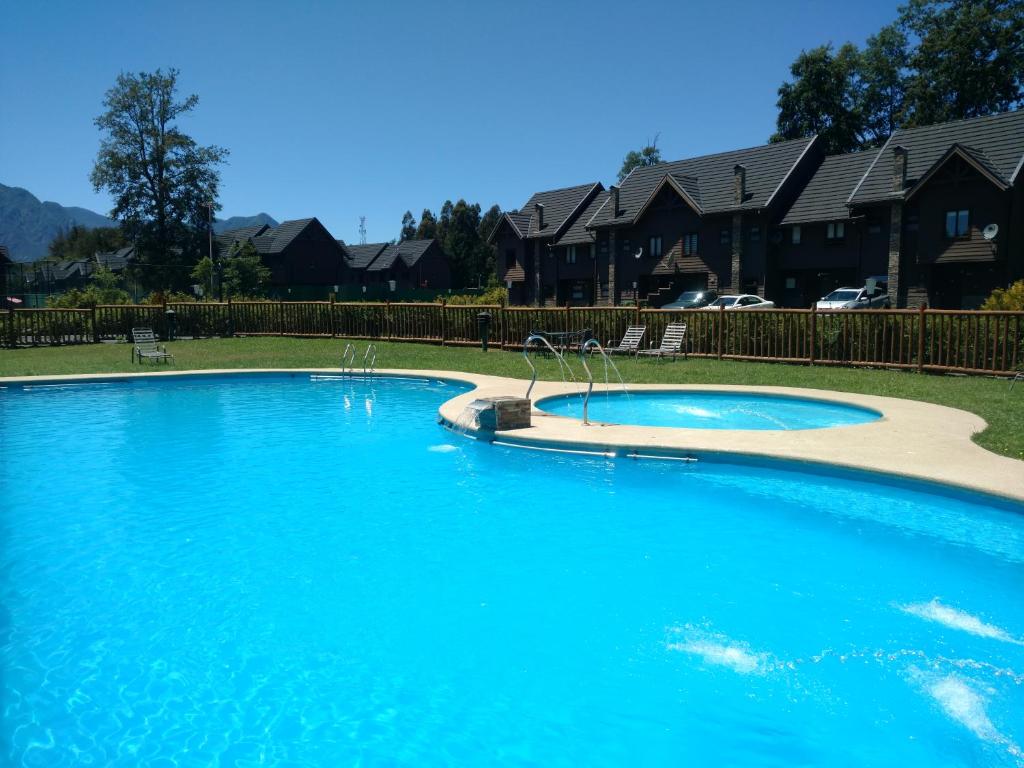 uma grande piscina azul num quintal com casas em Casa Condominio Alicura Pucón em Pucón