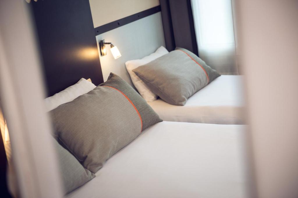 a bedroom with two beds with pillows and a mirror at Timhotel Paris du Gare du Nord in Paris