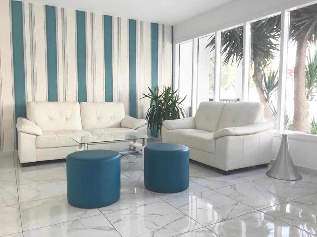 a living room with two white couches and blue stools at Margarita Napa Apartments in Ayia Napa