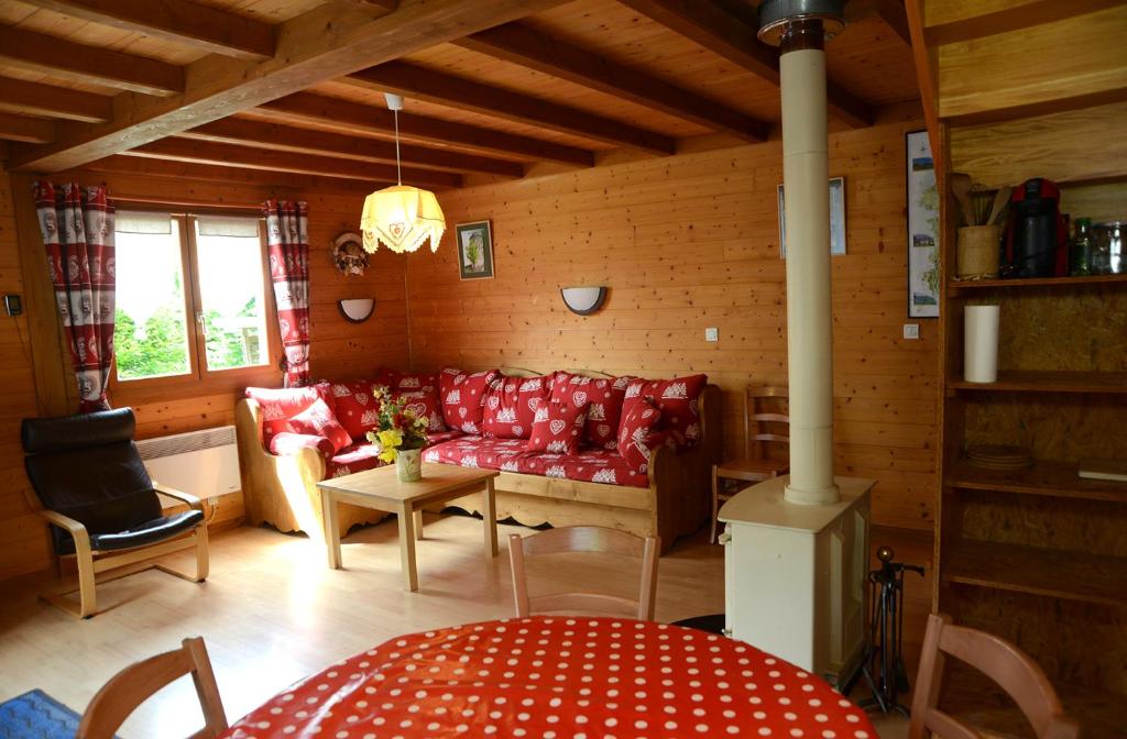 uma sala de estar com um sofá vermelho e uma mesa em chalet des planchettes em Marigny