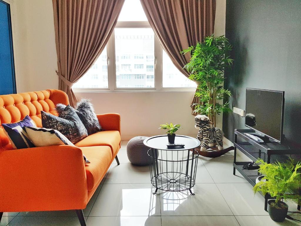 a living room with an orange couch and a tv at No.4 The Cave @ Puchong Skypod Residence in Puchong