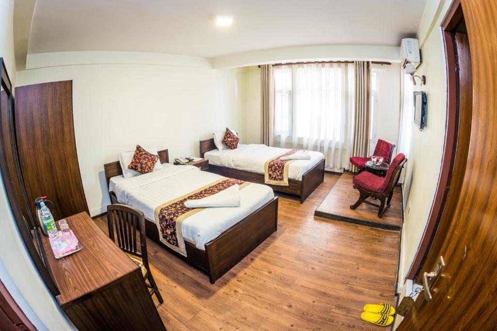 a hotel room with two beds and a chair at Hotel Yambu in Kathmandu