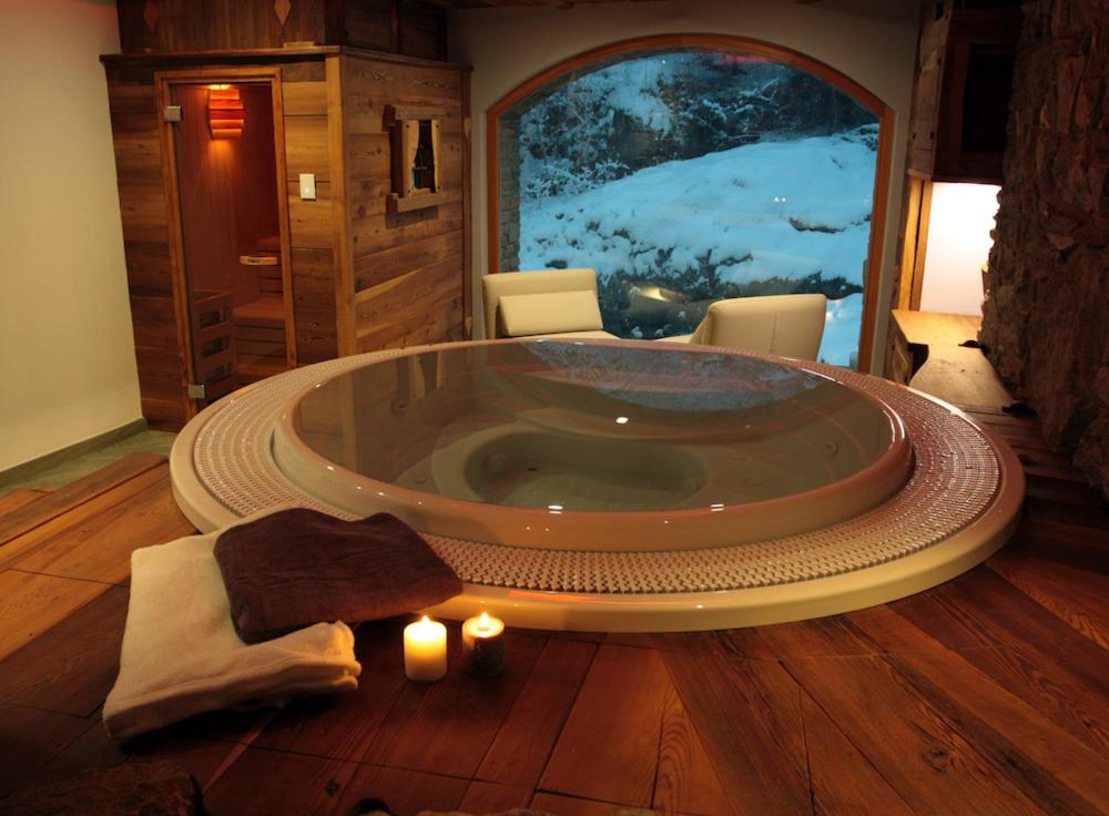 a jacuzzi tub in a room with a large window at Le Moulin Des Aravis in Pontboset