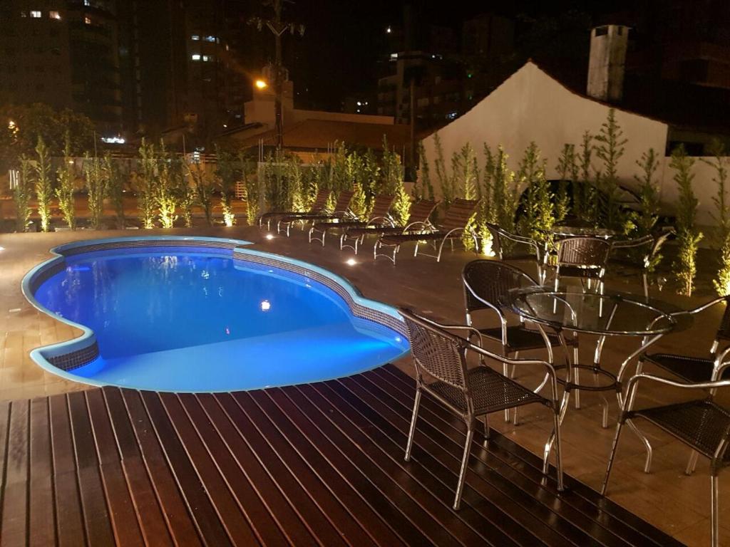 a swimming pool at night with chairs and a table at Casa de Oliveira Hostel in Torres