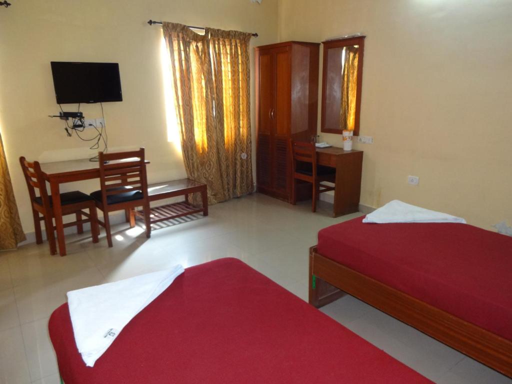 a bedroom with two beds and a table and a desk at Sea Shell Park in Chennai