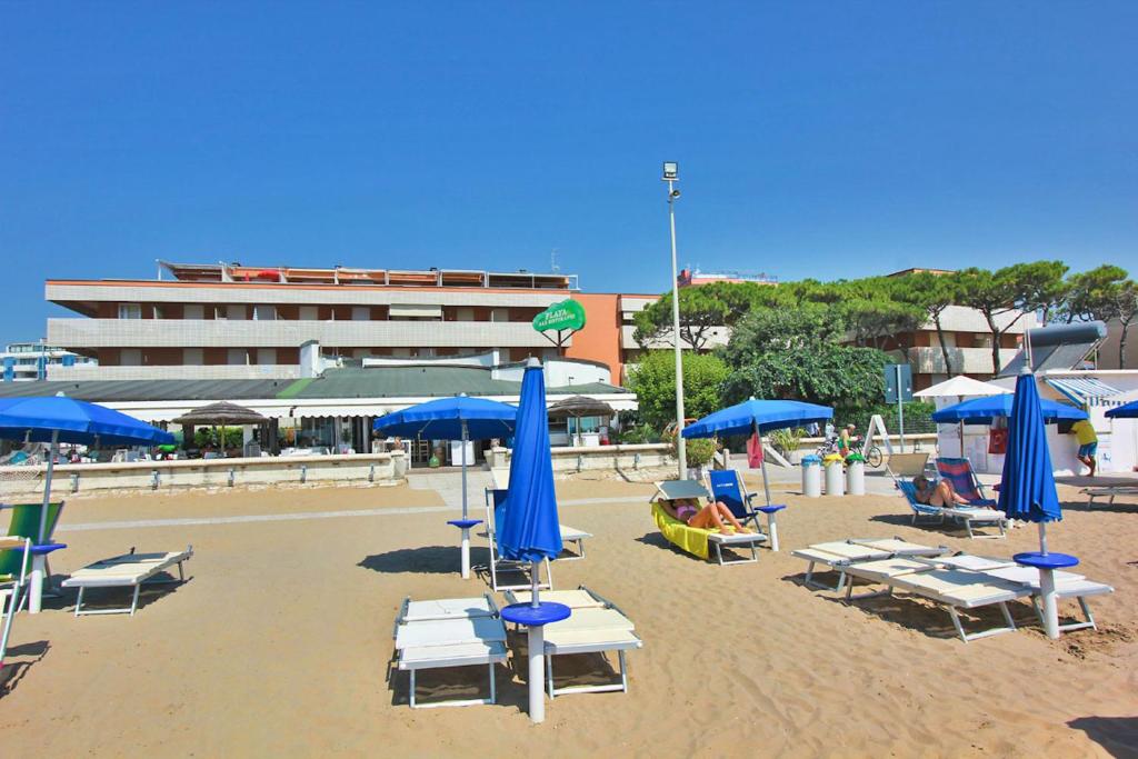una spiaggia con sedie e ombrelloni blu e bianchi di Condominio Casamare a Lignano Sabbiadoro