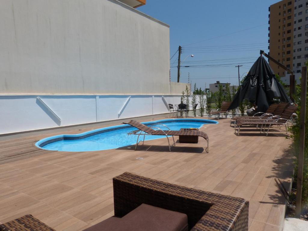 a patio with a pool and chairs and an umbrella at Casa de Oliveira Hostel in Torres
