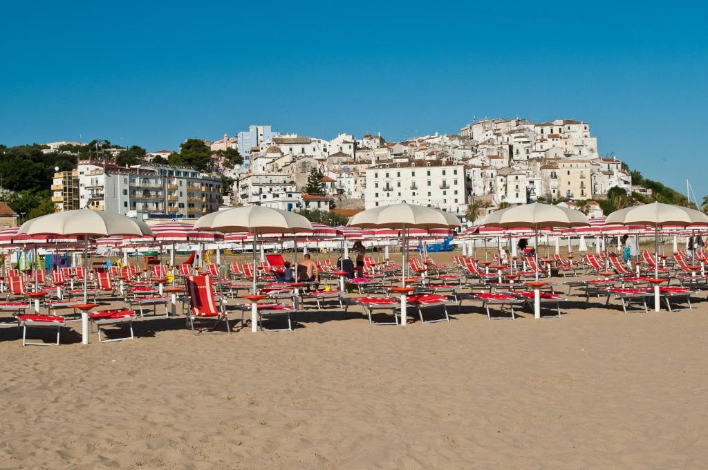 un gruppo di sedie e ombrelloni in spiaggia di Hotel Borgo Marina a Rodi Garganico