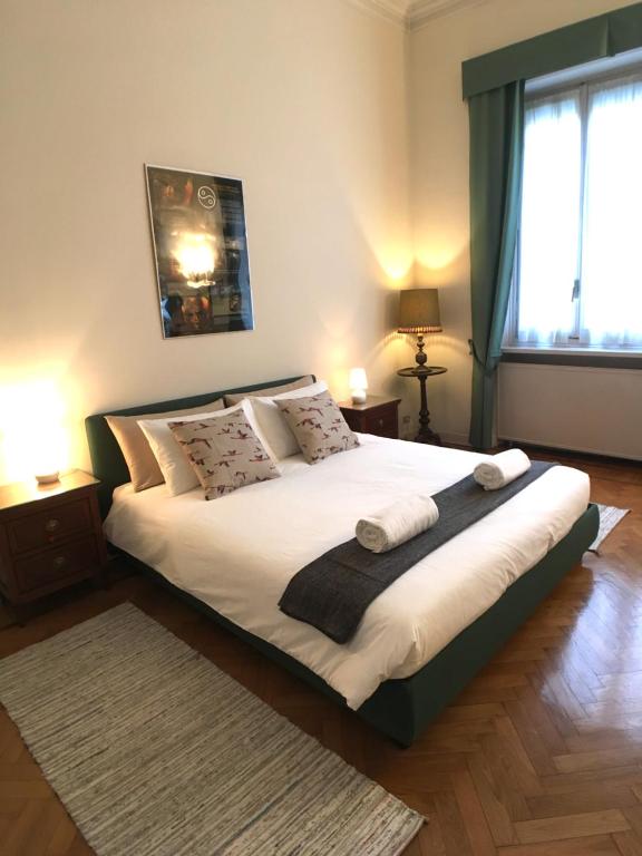 um quarto com uma cama grande com lençóis brancos e almofadas em Appartamenti Politecnico em Turim