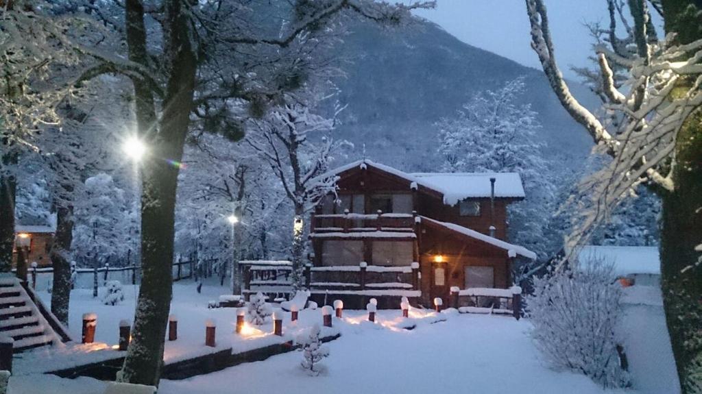 una cabaña en la nieve con una montaña en Posada del Valle en Ushuaia