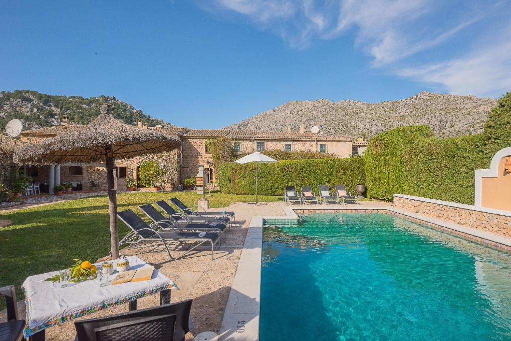 a house with a swimming pool with chairs and an umbrella at VILLA L'Hort - Traditional restored house in Pollença