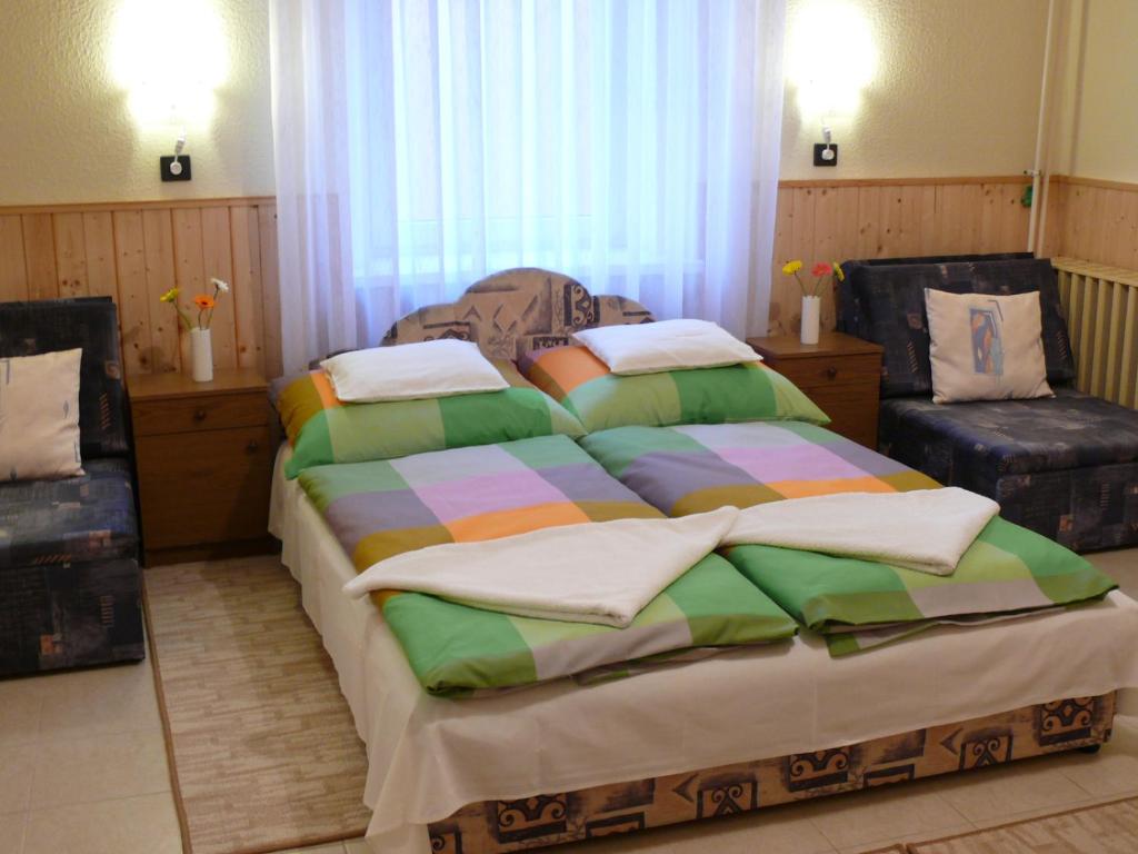 1 Schlafzimmer mit einem großen Bett und 2 Stühlen in der Unterkunft Madácsi Vendégház in Kiskőrös