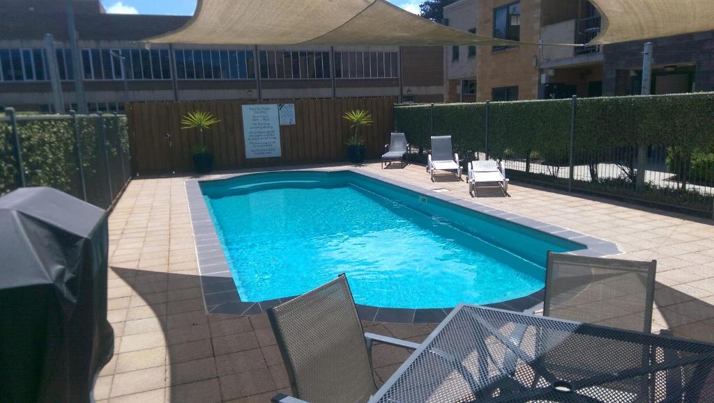 a swimming pool with two chairs at Gilles St Apartments in Warrnambool