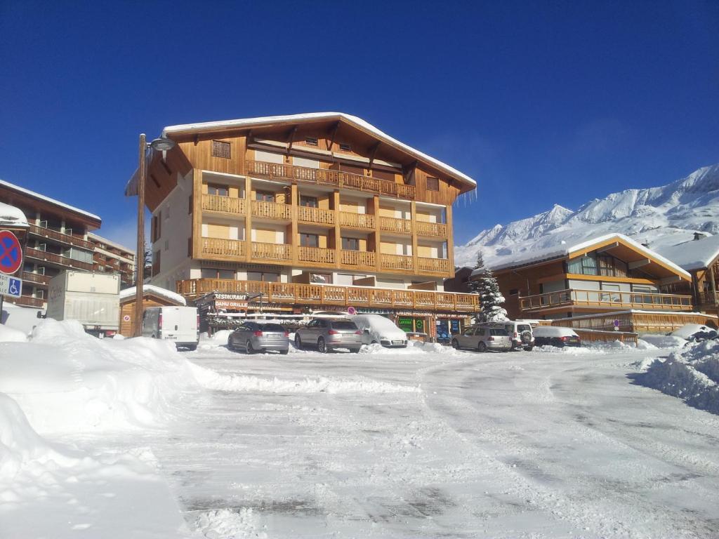 un aparcamiento cubierto de nieve frente a un hotel en La Dauphinoise Alpe d'Huez en L'Alpe-d'Huez