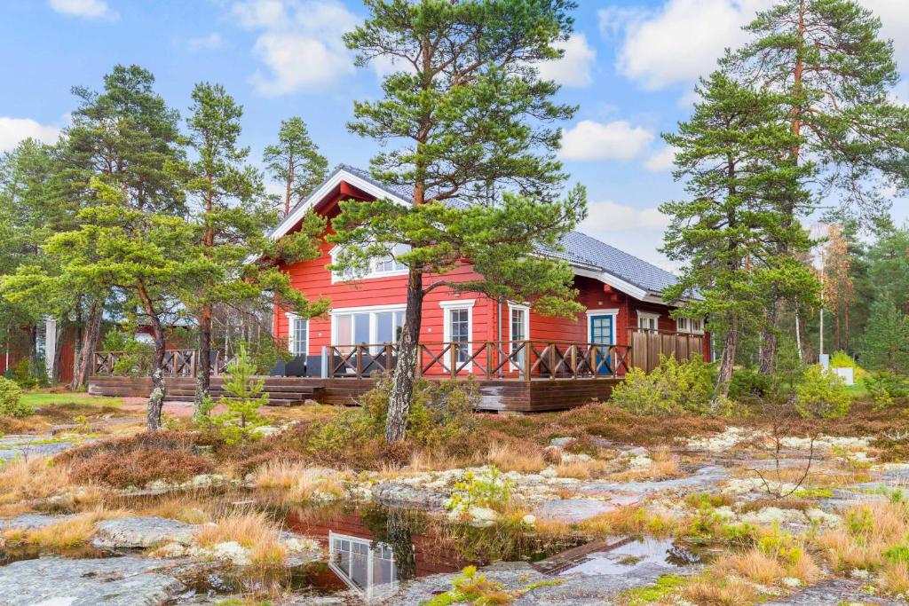 une maison rouge dans les bois avec des arbres dans l'établissement Villa Älgen, à Bamböle