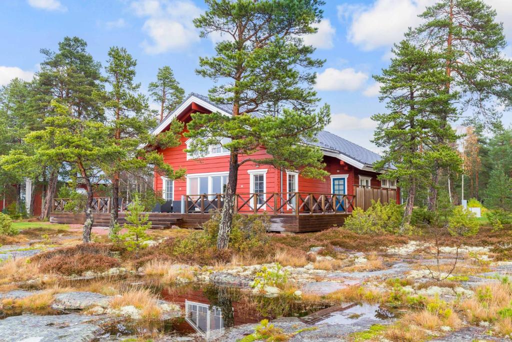 ein rotes Haus im Wald mit Bäumen in der Unterkunft Villa Älgen in Bamböle