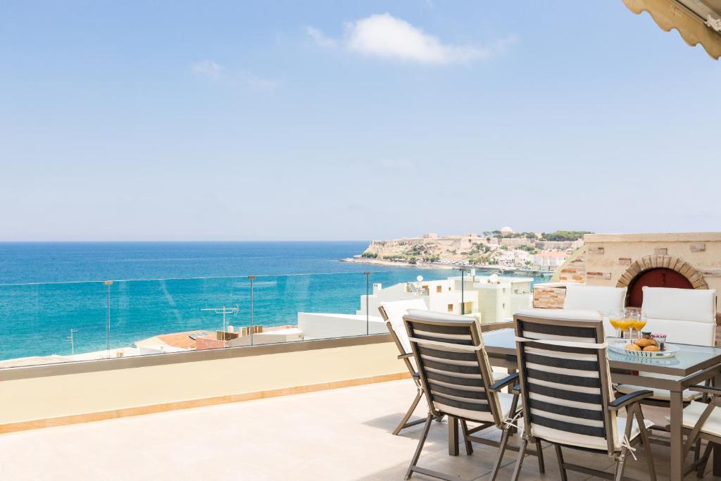 罗希姆诺Elytis Panoramic View的阳台配有桌椅,俯瞰着大海