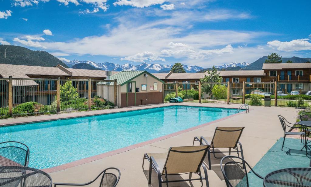 - une piscine avec des chaises longues et des montagnes en arrière-plan dans l'établissement Blue Door Inn, à Estes Park
