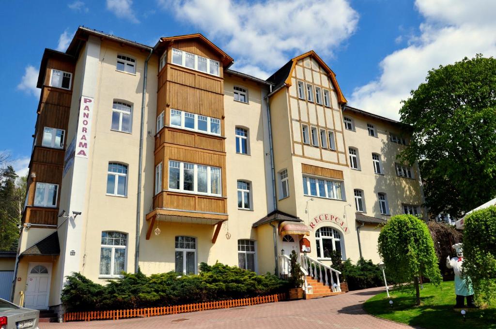 un gran edificio con una mujer parada frente a él en Pensjonat Panorama, en Polanica-Zdrój