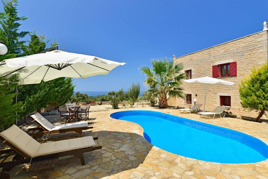 a villa with a swimming pool and an umbrella at Grecian Villas Chania in Delimanolianá