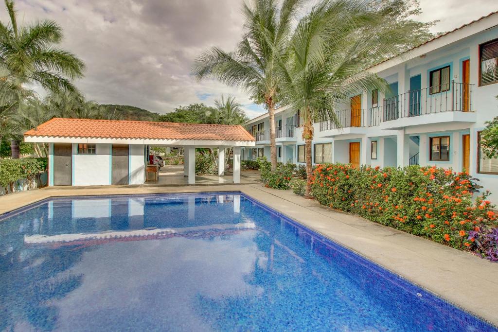 a swimming pool in front of a house with palm trees at Aquamarine 4 in Guanacaste