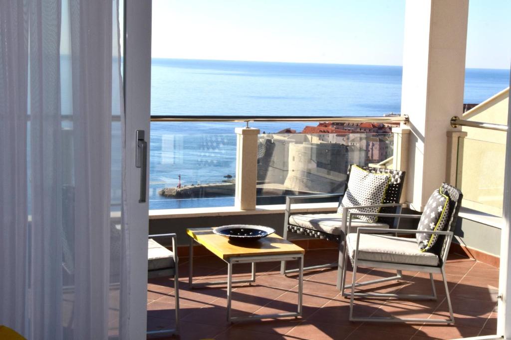 een balkon met stoelen en een tafel en uitzicht op de oceaan bij 87 Stairs Apartments in Dubrovnik