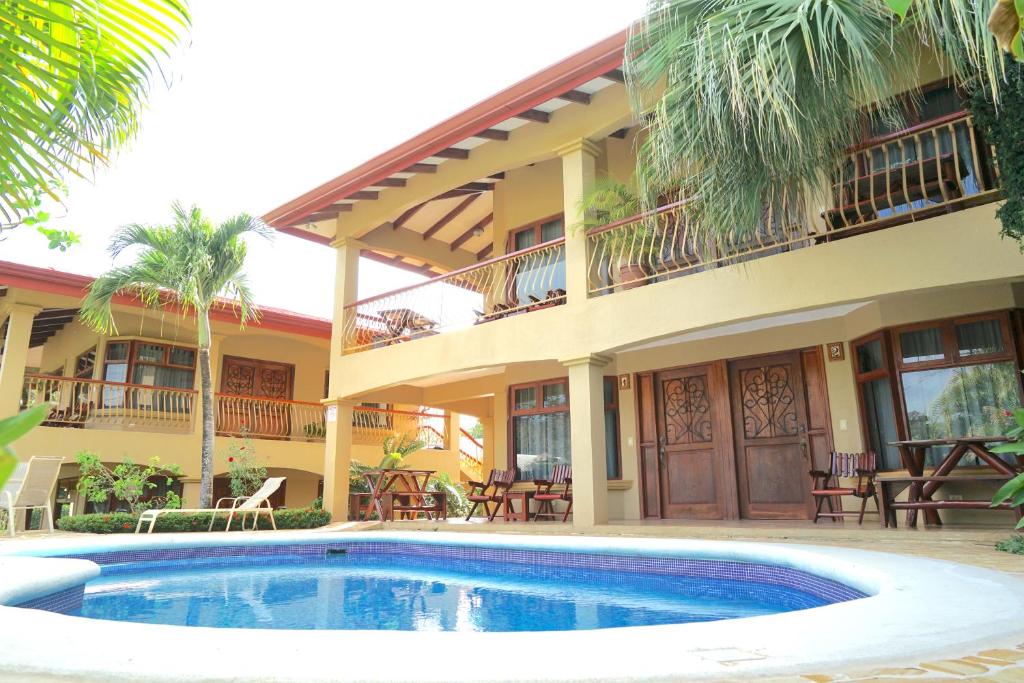 a building with a swimming pool in front of a house at Villas Welcome to Heaven in Carrillo