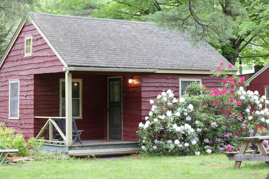 een rood tiny house met een veranda en bloemen bij Phoenicia Lodge in Phoenicia
