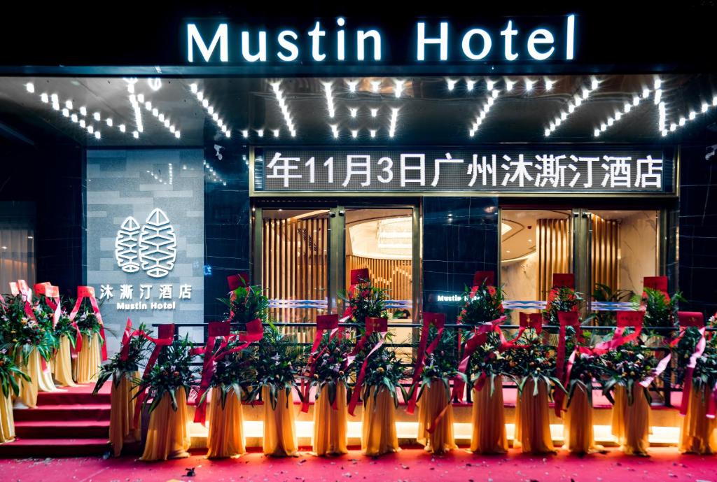 un hotel con un montón de plantas delante de él en Guangzhou Mustin Hotel, en Guangzhou