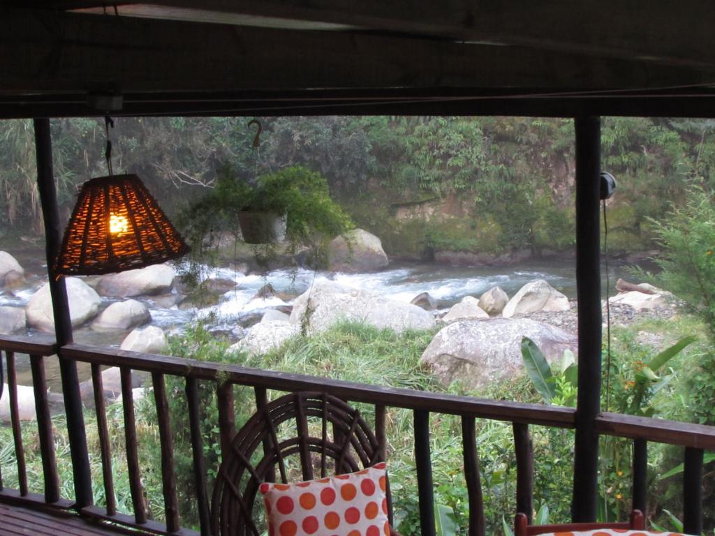 un porche con lámpara y vistas al río en Arroyo Frío River Lodge en Arroyo Frío