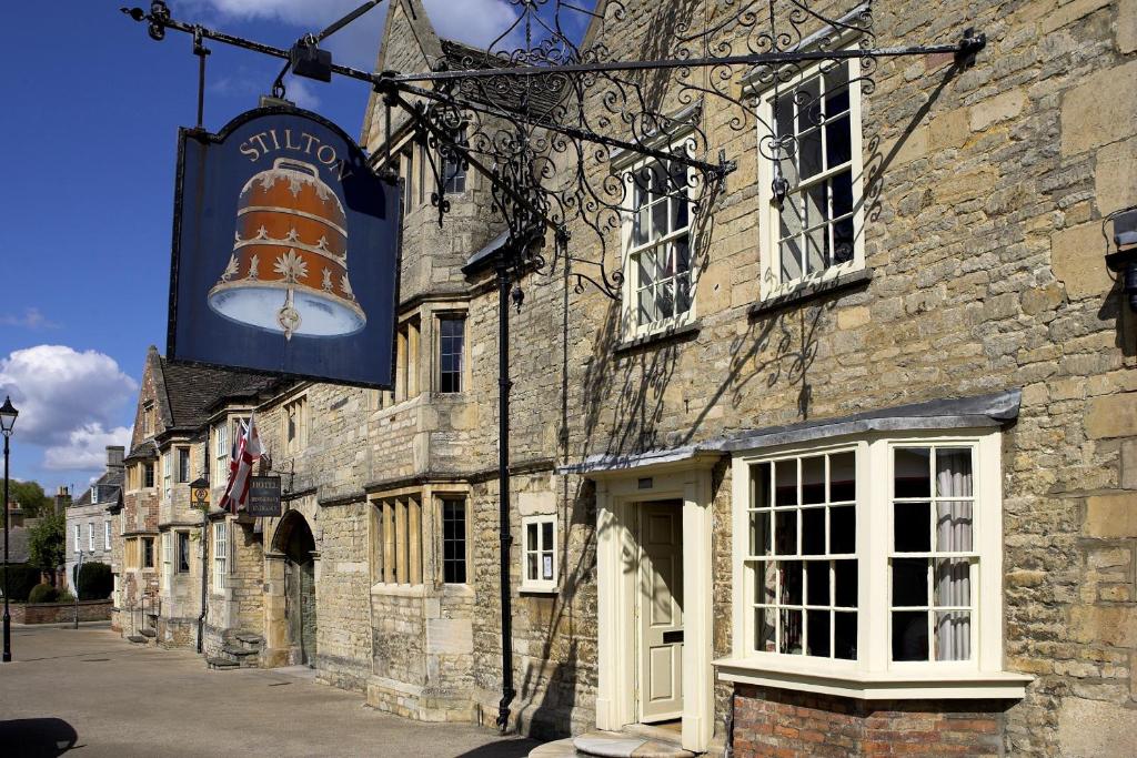 ピーターバラにあるThe Bell Inn, Stilton, Cambridgeshireの大看板が立つ古い石造りの建物