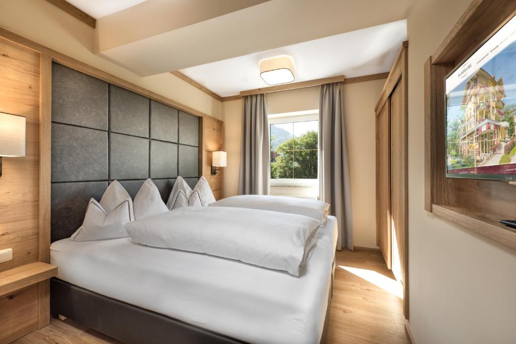 sypialnia z dużym białym łóżkiem i telewizorem w obiekcie Appartement Hotel Panorama-im Bademantel direkt in die Alpentherme w mieście Bad Hofgastein