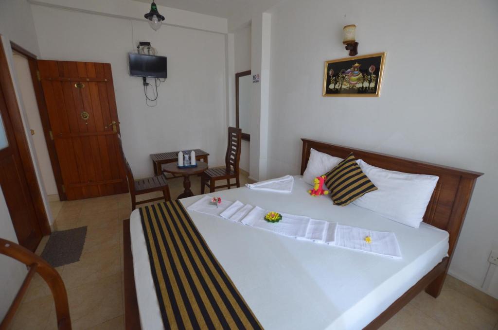 a bedroom with a large white bed with two chairs at Sihilro Regency in Udawalawe