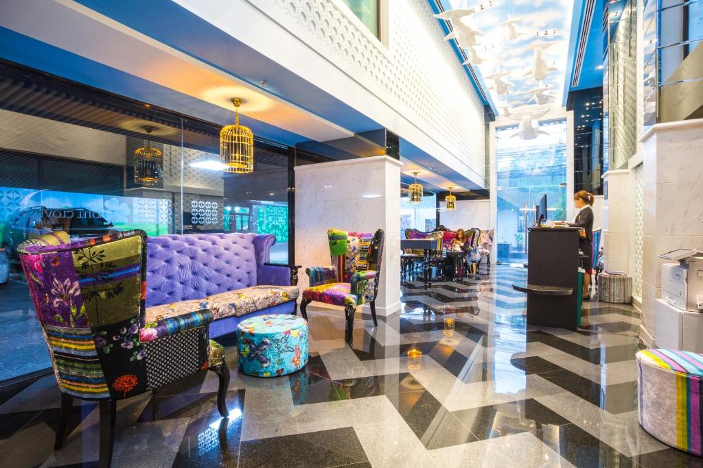 a lobby with a purple couch and chairs and a table at Hotel Clover Asoke - SHA Extra Plus in Bangkok