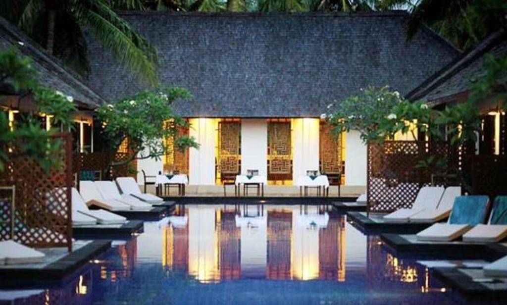 a pool with white lounge chairs in a resort at Luce d'Alma Suites Resort & Spa in Gili Trawangan