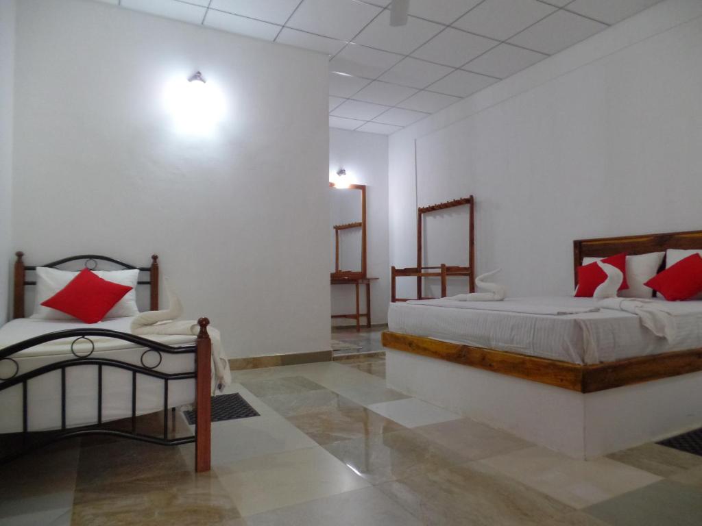 um quarto com 2 camas com almofadas vermelhas em Amaya River Side Homestay em Sigiriya