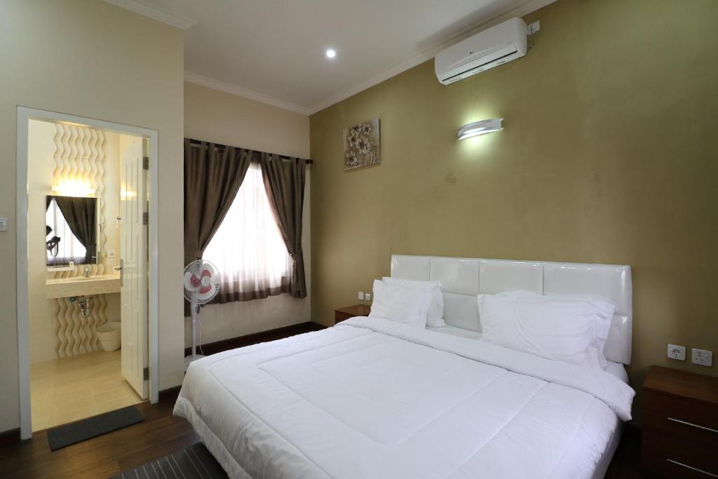 ein Schlafzimmer mit einem großen weißen Bett und einem Fenster in der Unterkunft Diyar Villas Puncak M6/14 in Puncak