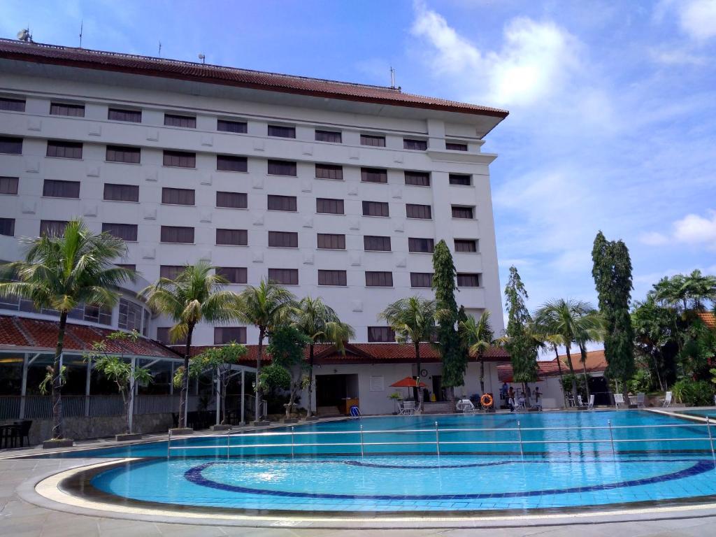 a hotel with a large swimming pool in front of a building at The Sunan Hotel Solo in Solo