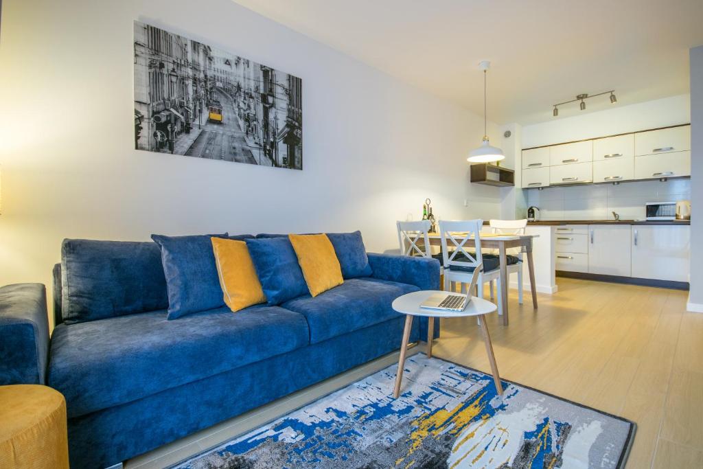 a living room with a blue couch and a kitchen at Apartament Darłówko in Darlowko