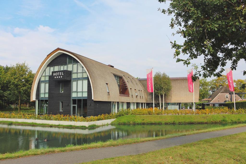 een groot gebouw naast een waterlichaam bij Hotel De Roode Schuur in Nijkerk