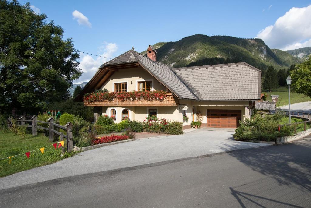 a house with flowers in front of a driveway at Apartments Rožič Bohinj in Bohinj