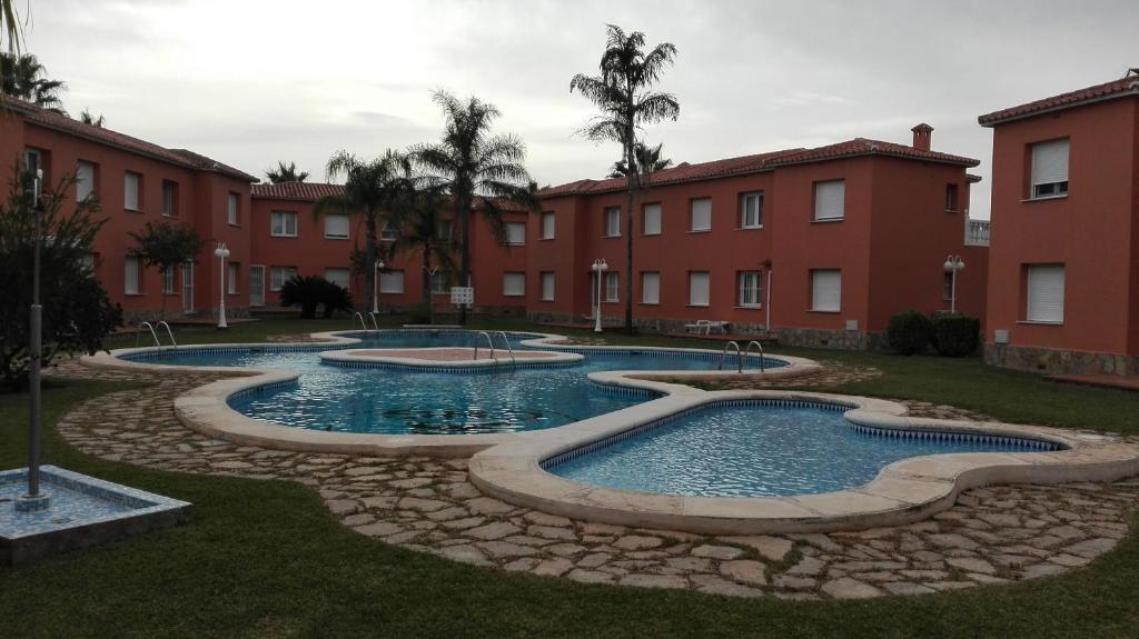 a group of three pools in a courtyard with buildings at Apartamento entero 3 Habitaciones CLUB SEVILLA III in Casas Devesa