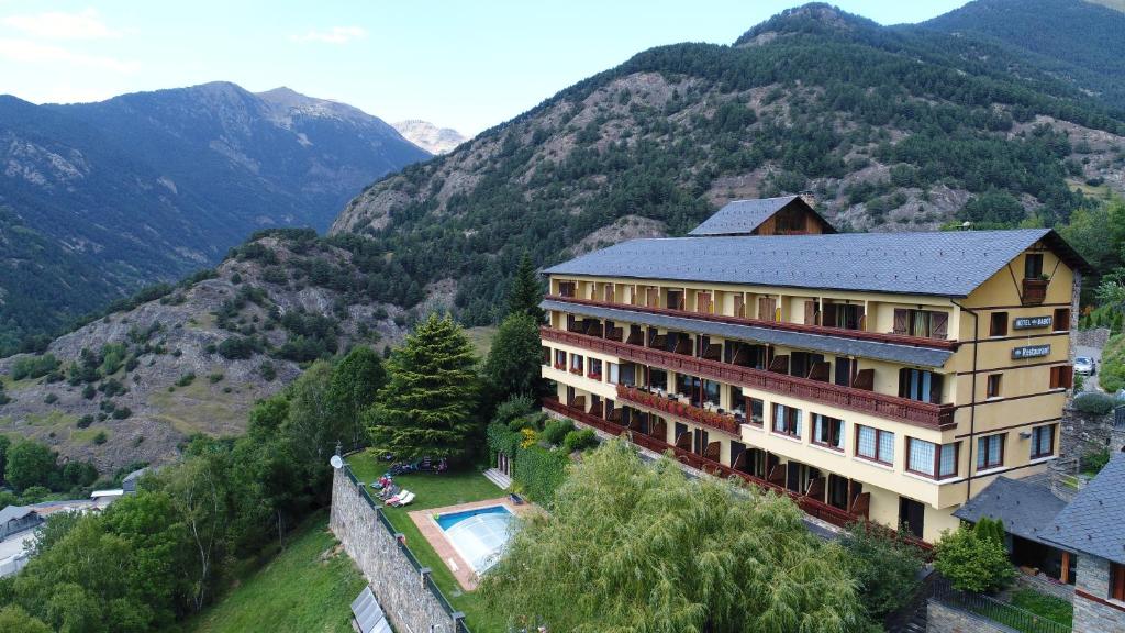 a building with a swimming pool and mountains in the background at Abba Ordino Babot Hotel in Ordino