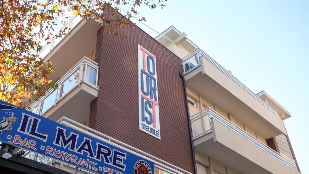 a building with a sign on the side of it at Hotel Tourist Meuble in Rimini